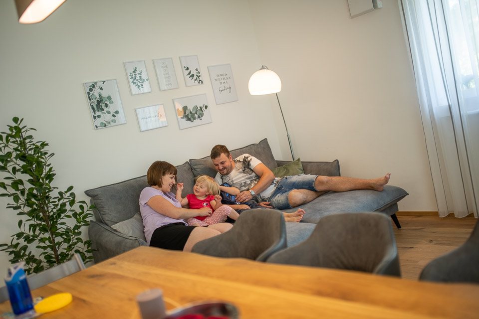Familie gemeinsam entspannt auf dem Sofa im Wohnzimmer
